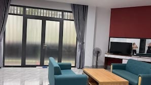 Un salon moderne doté d’une grande porte-fenêtre coulissante, d’un téléviseur à écran plat et de deux canapés de couleur turquoise.