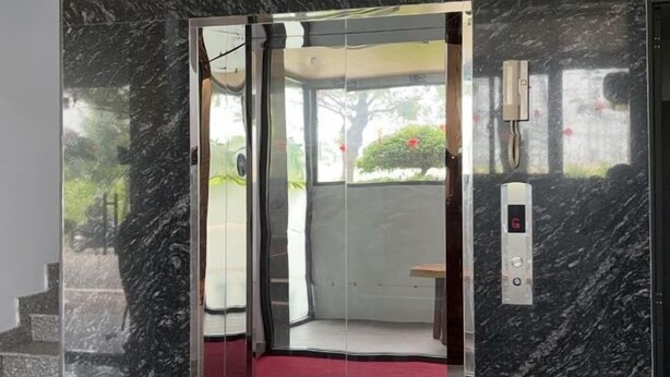 Un ascenseur doté d’une porte en verre, d’un tapis rouge et d’un mur en marbre.