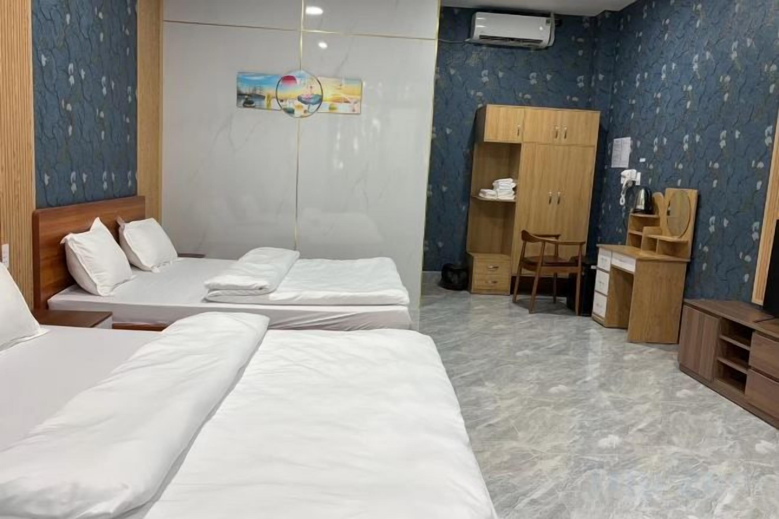 Een hotelkamer met twee bedden, een bureau, een stoel, een kledingkast en een klein kastje.