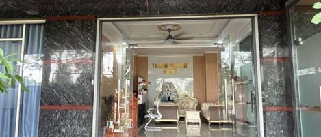 A hotel entrance with a glass door, a ceiling fan, and red hanging decorations.