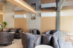 A modern interior with seating arrangements, air conditioning units, and a glass partition. - Banana Guesthouse (Pattaya)