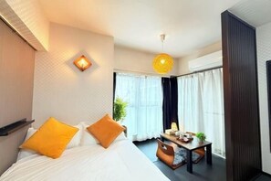 Ett hotellrum med en säng, ett litet bord och en hängande lampa.