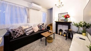 Una sala de estar con sofá, mesa de centro, chimenea y televisor.