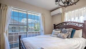 Un dormitorio con una cama grande, cabecera de madera y vistas a una casa por la ventana.
