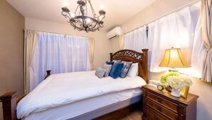 Un dormitorio con cama, mesita de noche de madera, lámpara y candelabro.