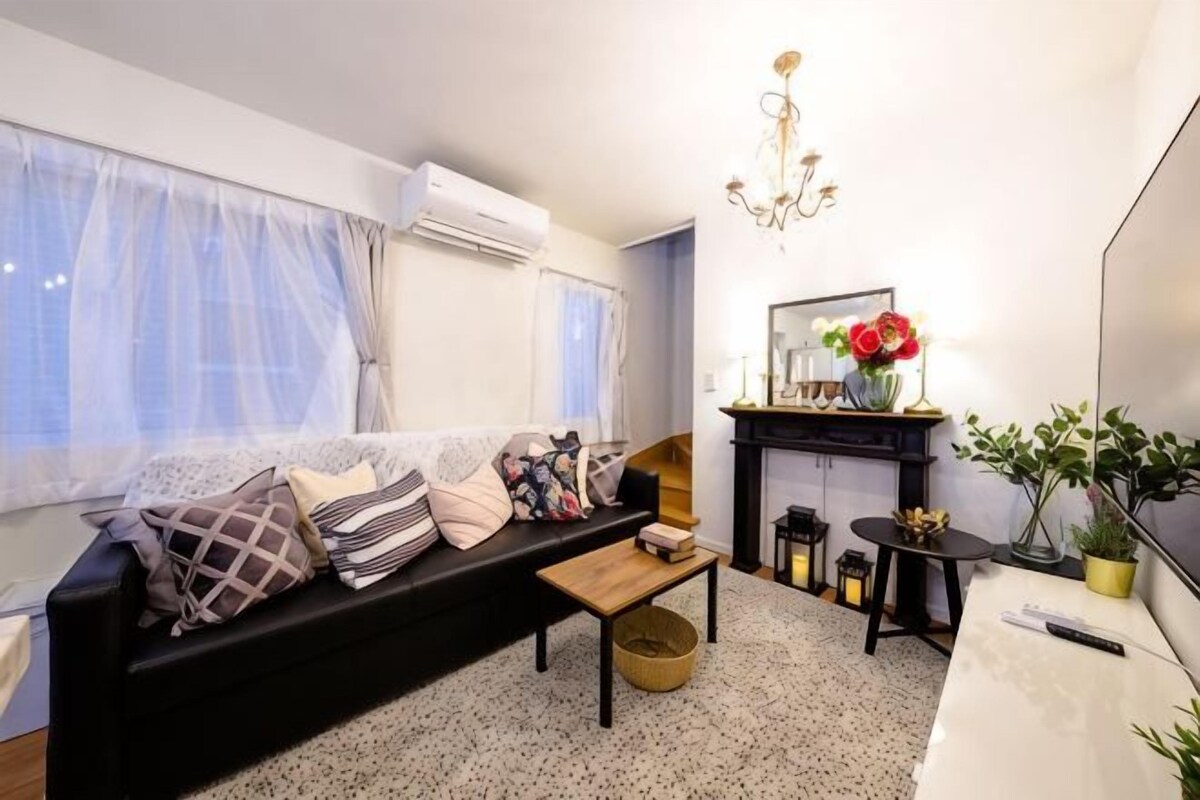 Una sala de estar con sofá, mesa de centro, chimenea y televisor.