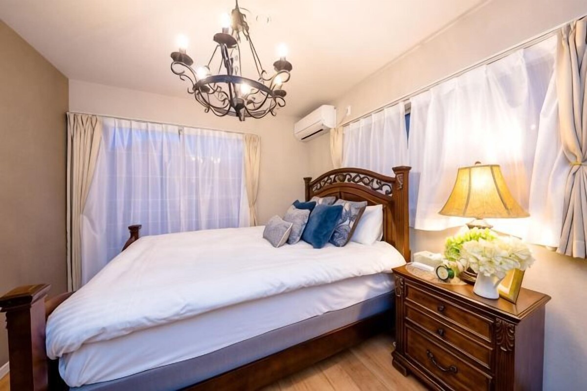 Un dormitorio con cama, mesita de noche de madera, lámpara y candelabro.
