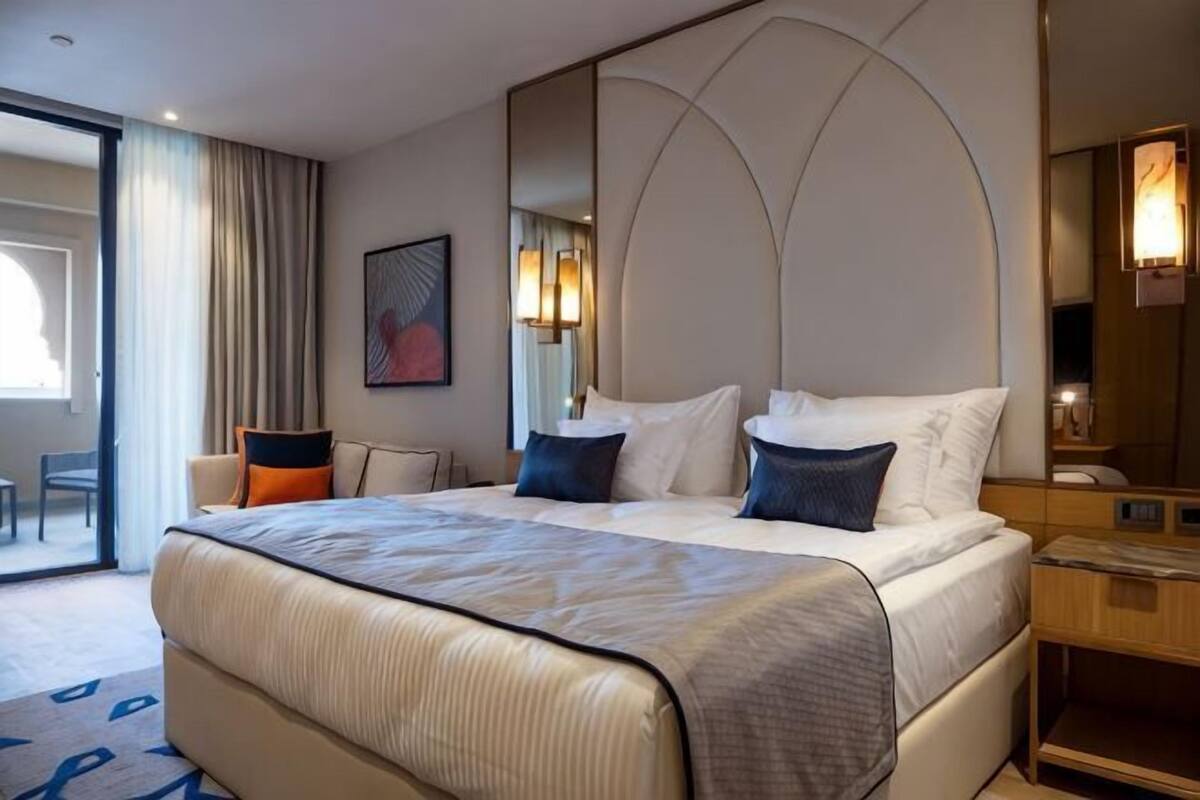 Ein Hotelzimmer mit einem großen Bett, einem Schreibtisch, einem Stuhl und einem großen Spiegel.