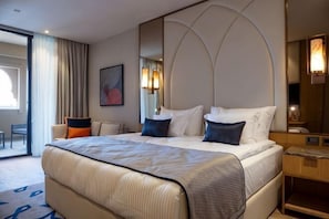 Una habitación de hotel con una cama grande, un escritorio, una silla y un espejo amplio.