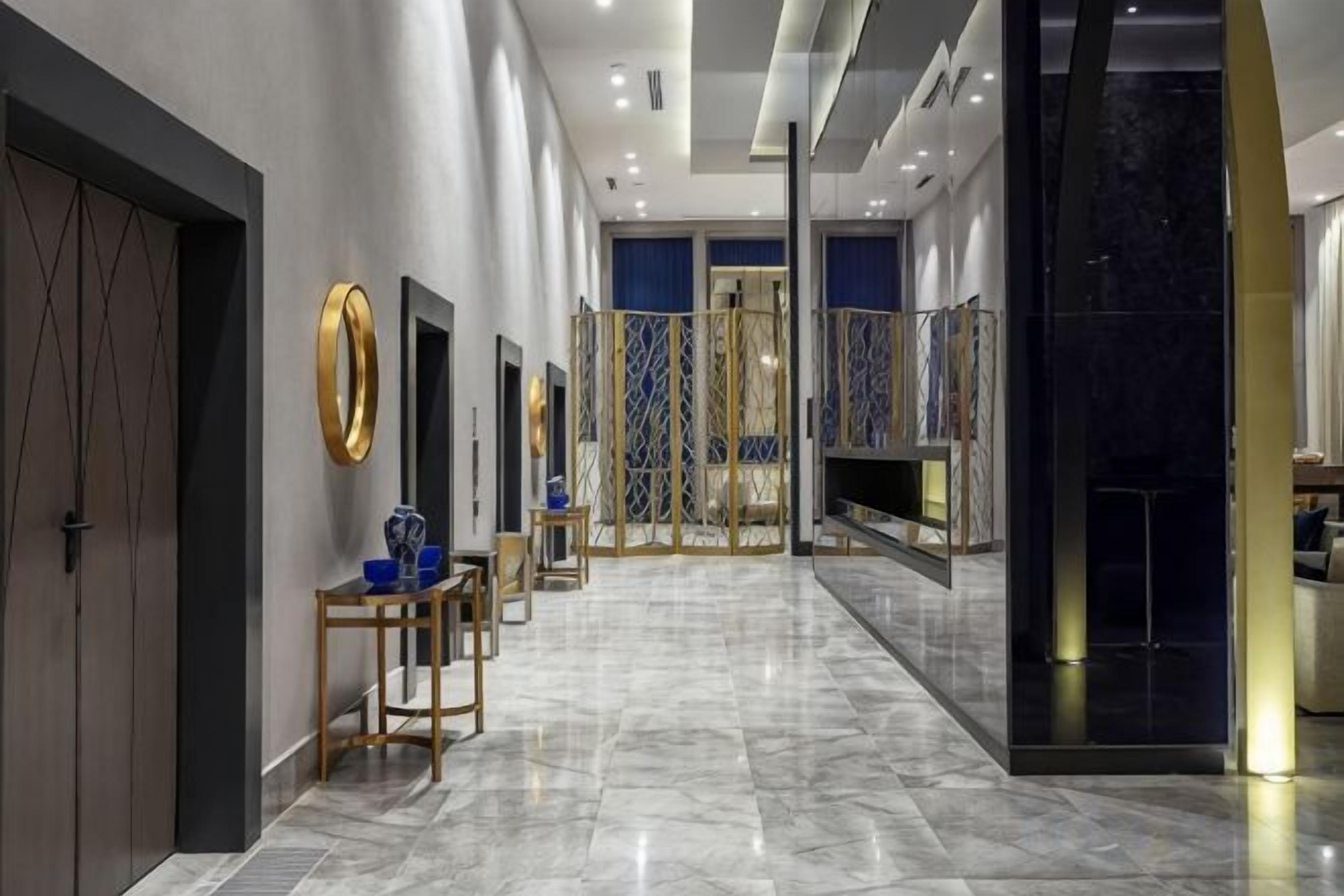 A hotel lobby with a marble floor, a reception desk, and a view of the lobby area.