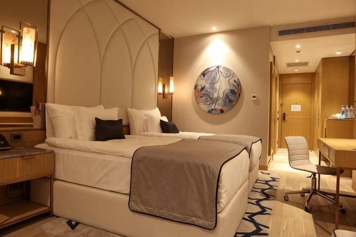 Ein Hotelzimmer mit einem großen Bett, einem Schreibtisch, einem Stuhl und einem Bild an der Wand.