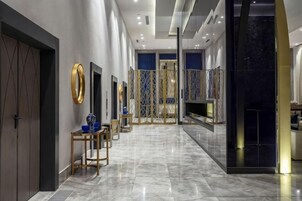 Un moderno hall de hotel con suelo de mármol, un mostrador de recepción y una pared decorativa.