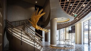 A spacious lobby with a grand staircase, a large golden sculpture, and a modern ceiling design. - KARAVANSARAY Turkistan Family Hotel - Free FLYING THEATRE Entrance (Turkistan)
