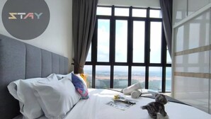 A hotel room with a large window, a bed with white linens, a grey headboard, and a small stuffed animal on the bed. - D'Pristine Homestay ByStay (Iskandar Puteri)