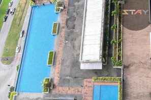 An aerial view of a hotel with a rectangular pool surrounded by a brick walkway, a covered area, and a building with a sign reading "STAY". - D'Pristine Homestay ByStay (Iskandar Puteri)