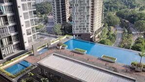 A residential building with a rooftop pool, surrounded by greenery and other high-rise buildings. - D'Pristine Homestay ByStay (Iskandar Puteri)