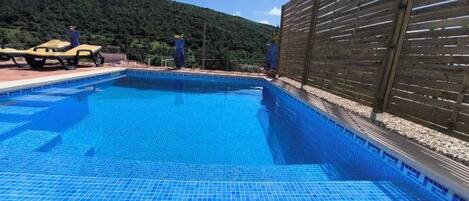 A swimming pool with a wooden fence and a person standing by the pool.