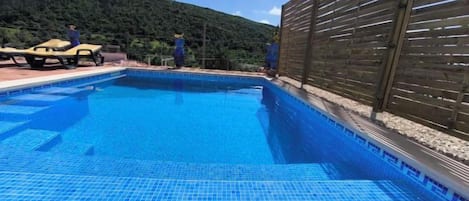 Una piscina con valla de madera y montañas al fondo.