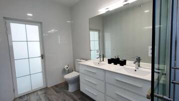 A modern bathroom with a white vanity, a large mirror, and a glass shower enclosure.