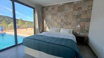 A bedroom with a large bed, a view of a swimming pool, and a patterned wall.
