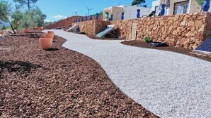 Un sendero que lleva a un edificio con un muro de piedra y una barandilla azul.