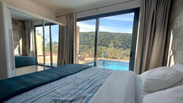 Habitación de hotel con cama, vista a una piscina y balcón.