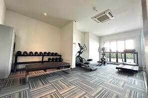 Une salle de sport équipée de matériel d’exercice, d’un banc et d’un tapis à motifs.