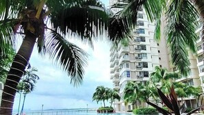 A swimming pool surrounded by palm trees and a high-rise building. - Astonishing Ocean View 4 Bedrooms Huge Balcony 2 Car Park (Johor Bahru)