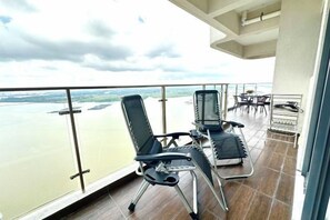 Ein Balkon mit zwei Stühlen und einem Tisch mit Blick auf einen Fluss.