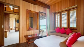 Una habitación con paneles de madera, una cama, un escritorio y un ventanal con contraventanas.
