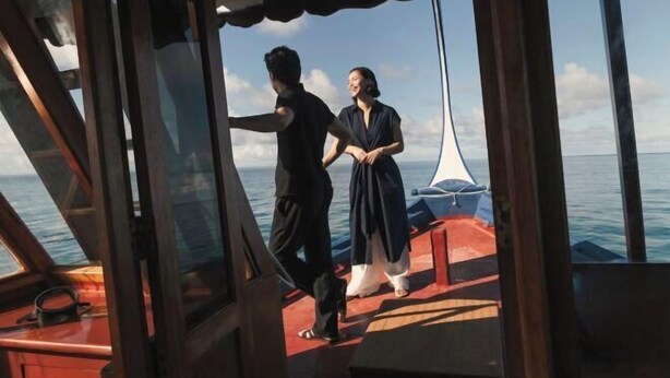Una pareja en la cubierta de un barco, con vista al mar.