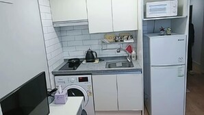 A compact kitchen with a washing machine, a microwave, and a small refrigerator. - Incheon Airport ANN Guesthouse (Incheon)