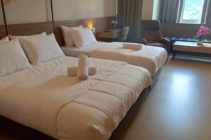 Una camera d'albergo con due letti, un comodino, una sedia e una finestra con tende.