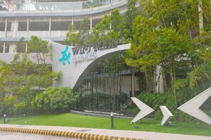 Un edificio con una entrada curva, un logotipo con una estrella y el texto 'WINDMILL', rodeado de follaje.