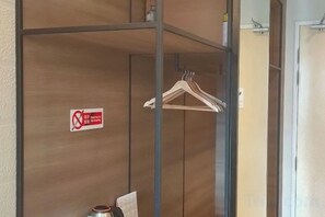 A wooden closet with a no-smoking sign, a wooden hanger, and a towel on the floor. - Windmills Upon Hills Hotels & Residences Genting Highland (Genting Highlands)