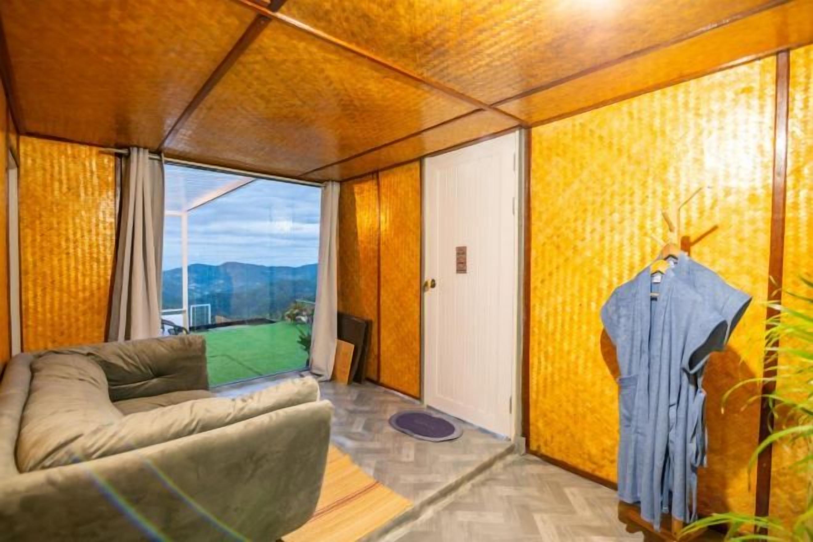 A room with a sofa, a door, and a view of the outdoors.