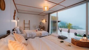 A bedroom with two beds, a large window, a balcony with plants, and a ladder. - Phutawan monjam (Mae Rim)