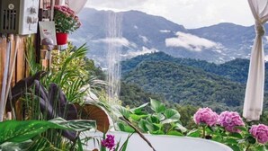A room with a view of mountains, a waterfall, and various plants. - Phutawan monjam (Mae Rim)
