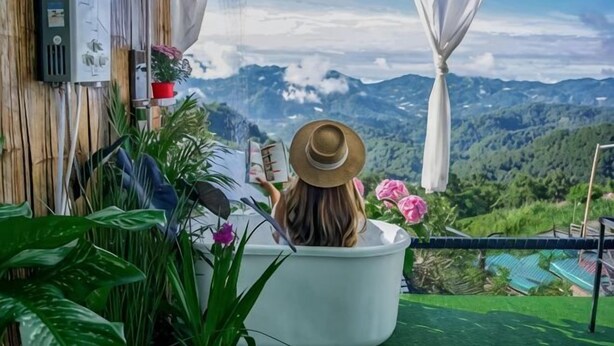 A person in a bathtub with a view of mountains. - Phutawan monjam (Mae Rim)