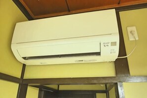 A white air conditioning unit mounted on a yellow wall with a visible control panel. - Asahi House (Osaka)
