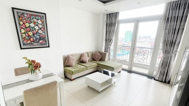 A modern living room with a sectional sofa, a dining table, and a coffee table. - Daily Apartment & Residence (Phnom Penh)