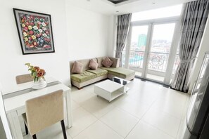 A modern living room with a sectional sofa, a dining table, and a coffee table. - Daily Apartment & Residence (Phnom Penh)
