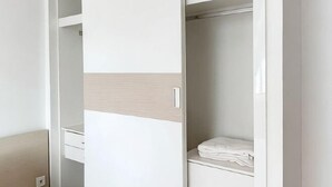 A white wardrobe with a light wood panel, a white shelf, and a folded white towel. - Daily Apartment & Residence (Phnom Penh)