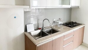 A kitchen with a double sink, a stove, and a microwave. - Daily Apartment & Residence (Phnom Penh)