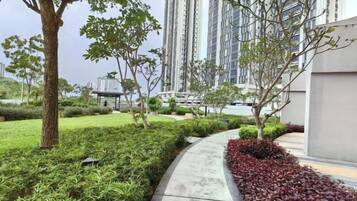 A landscaped pathway with greenery and a building in the background.