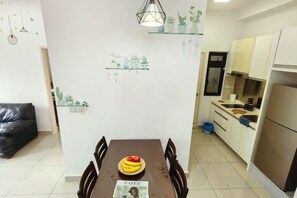 Un coin repas avec une table dressée pour quatre personnes, une cuisine avec des meubles blancs et un réfrigérateur.