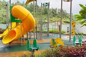 Une aire de jeux avec un toboggan jaune et des structures d’escalade.