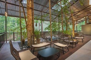 An outdoor seating area with wicker furniture and a view of the forest. - Rompin Rainforest Lodge (Rompin)