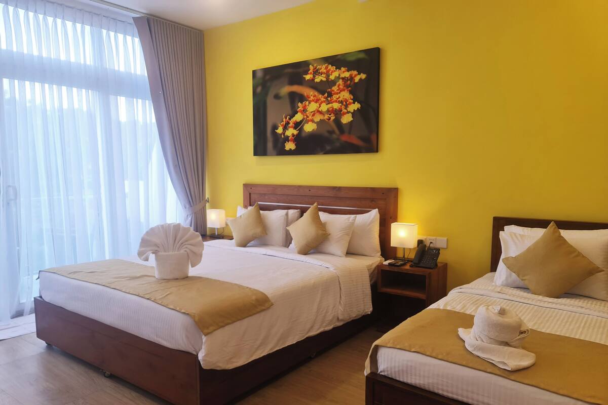 Une chambre d’hôtel avec deux lits, une tête de lit en bois, une table de chevet avec une lampe et un tableau représentant des fleurs accroché au mur.