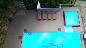 Ein Pool auf dem Dach mit klarem, blauem Wasser, einem Liegebereich und einem kleinen Billardtisch.